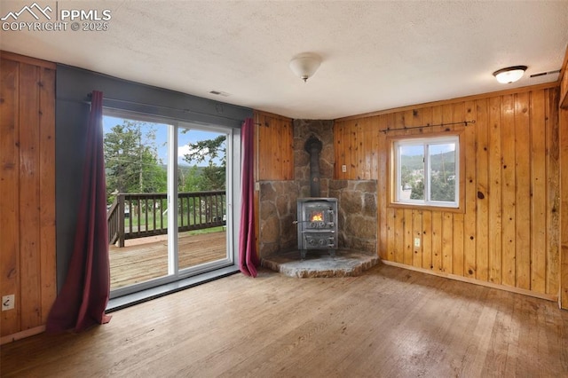 205 N Laurel St, Woodland Park, CO 80863 - unfurnished living room featuring wood finished floors, a wood stove, a textured ceiling, and wooden walls
