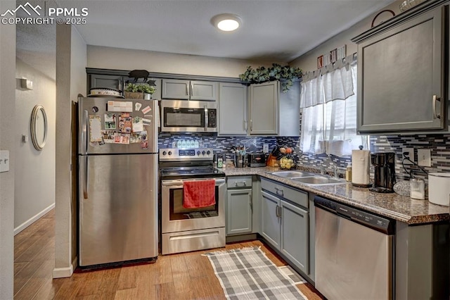 1222 Hartford St, Colorado Springs, CO 80906 - kitchen with appliances with stainless steel finishes, gray cabinetry, decorative backsplash, and light wood-style flooring