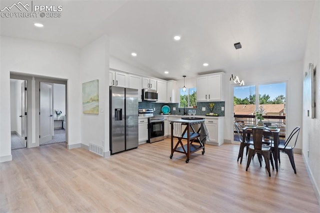 4615 Anjelina Cir, Colorado Springs, CO 80916 - kitchen with stainless steel appliances, backsplash, white cabinets, light wood-style floors, and pendant lighting