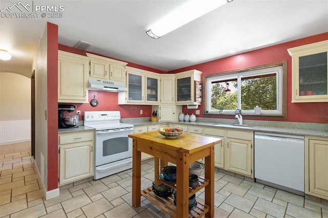 4115 Hay Creek Rd, Colorado Springs, CO 80921 - kitchen with white appliances, under cabinet range hood, light countertops, arched walkways, and glass insert cabinets