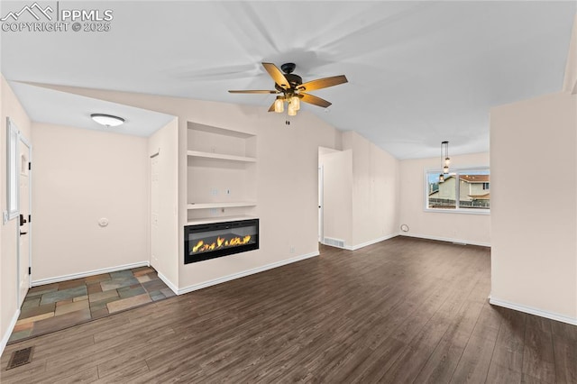 1005 Mountain View Rd, Woodland Park, CO 80863 - unfurnished living room with built in shelves, a ceiling fan, dark wood-type flooring, and a glass covered fireplace