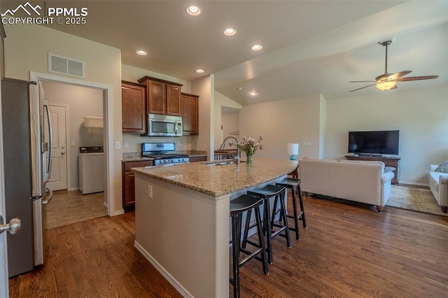 17529 Old Cherokee Trl, Colorado Springs, CO 80921 - kitchen featuring appliances with stainless steel finishes, washer / clothes dryer, dark wood-type flooring, light stone countertops, and a ceiling fan