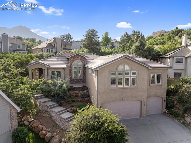 2585 Dunfries Ct, Colorado Springs, CO 80919 - view of front of house with a garage, concrete driveway, stucco siding, a tiled roof, and a mountain view