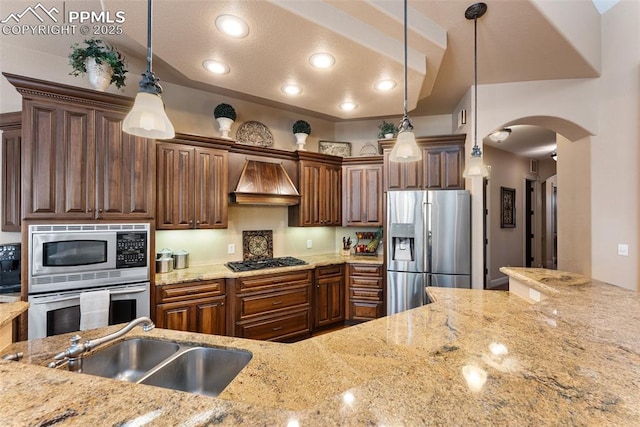 2585 Dunfries Ct, Colorado Springs, CO 80919 - kitchen featuring appliances with stainless steel finishes, arched walkways, custom range hood, light stone counters, and decorative light fixtures