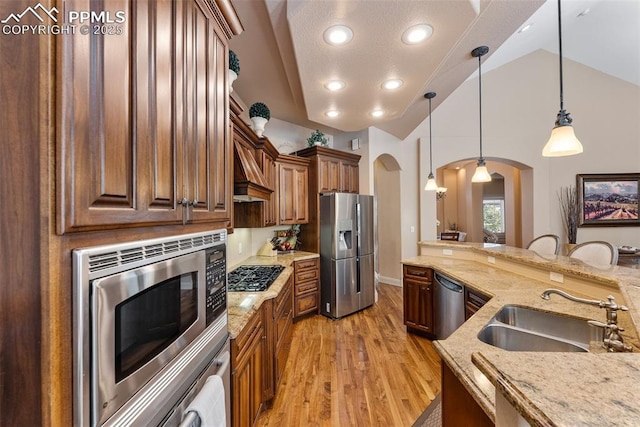2585 Dunfries Ct, Colorado Springs, CO 80919 - kitchen with stainless steel appliances, arched walkways, light wood finished floors, light stone countertops, and pendant lighting