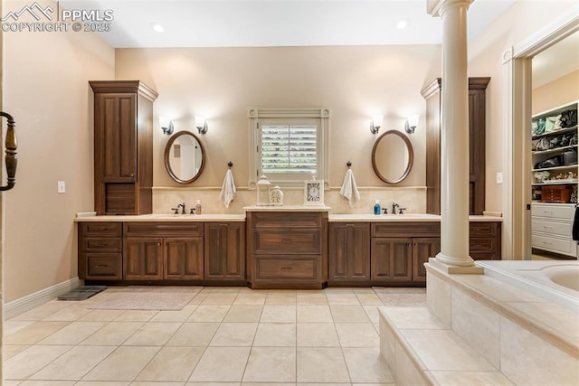 2585 Dunfries Ct, Colorado Springs, CO 80919 - bathroom featuring decorative columns, double vanity, tile patterned floors, and tiled tub