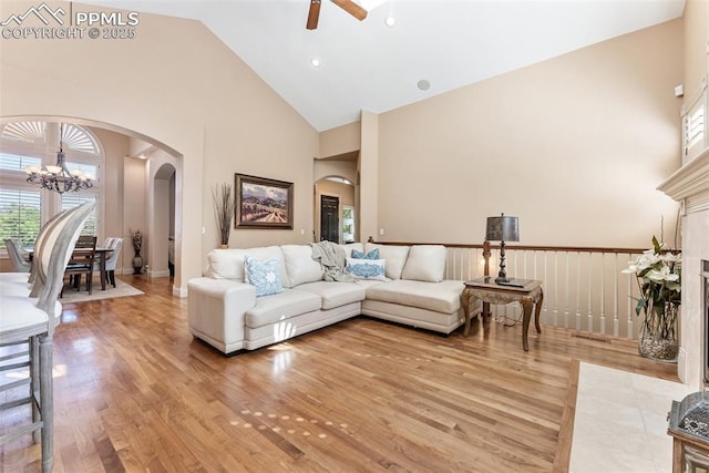 2585 Dunfries Ct, Colorado Springs, CO 80919 - living room with high vaulted ceiling, arched walkways, a ceiling fan, a chandelier, and light wood finished floors