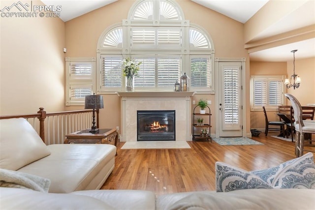 2585 Dunfries Ct, Colorado Springs, CO 80919 - living area featuring a chandelier, wood finished floors, a tiled fireplace, and high vaulted ceiling