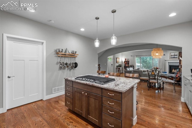 501 N Franklin St, Colorado Springs, CO 80903 - kitchen with stainless steel gas stovetop, arched walkways, wood finished floors, a warm lit fireplace, and recessed lighting