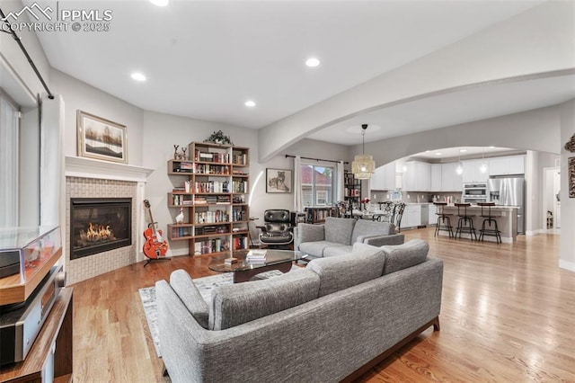 501 N Franklin St, Colorado Springs, CO 80903 - living area featuring arched walkways, a tiled fireplace, recessed lighting, and light wood-style flooring