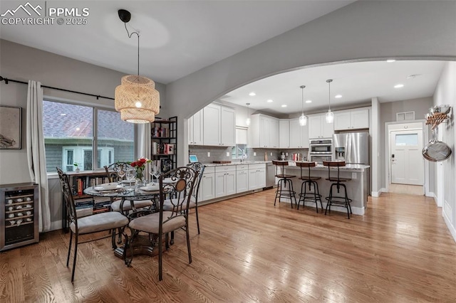 501 N Franklin St, Colorado Springs, CO 80903 - dining space featuring wine cooler, arched walkways, light wood-type flooring, and recessed lighting