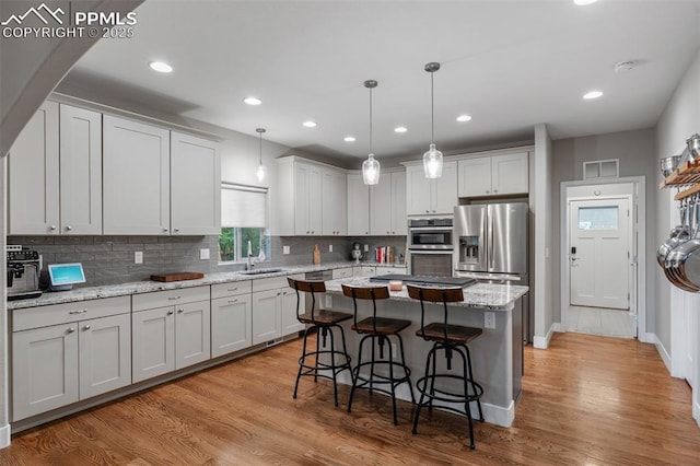 501 N Franklin St, Colorado Springs, CO 80903 - kitchen featuring stainless steel fridge with ice dispenser, decorative backsplash, a kitchen breakfast bar, light wood-style floors, and a center island