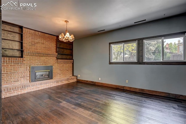5926 Del Paz Dr, Colorado Springs, CO 80918 - unfurnished living room featuring wood finished floors, a chandelier, built in features, and a fireplace