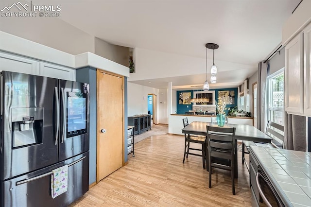 6931 Mcewan St, Colorado Springs, CO 80922 - kitchen featuring fridge with ice dispenser, lofted ceiling, tile counters, light wood finished floors, and hanging light fixtures