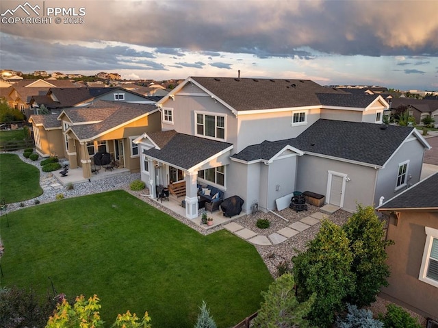 4296 New Santa Fe Trl, Colorado Springs, CO 80924 - back of property at dusk featuring a patio area, stucco siding, a residential view, a shingled roof, and a lawn