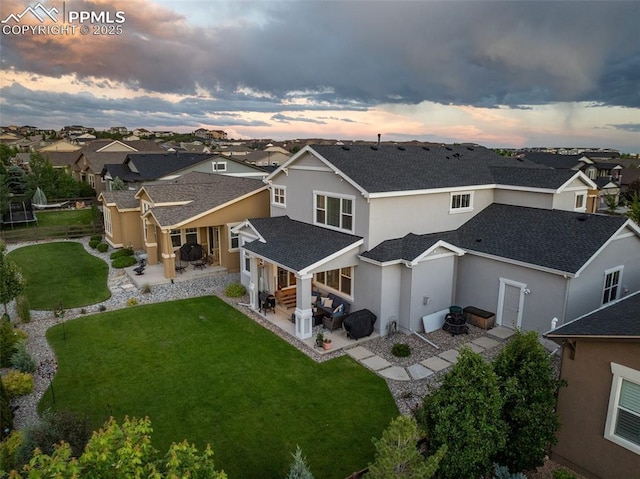 4296 New Santa Fe Trl, Colorado Springs, CO 80924 - back of property at dusk with a patio, a shingled roof, a residential view, stucco siding, and a yard