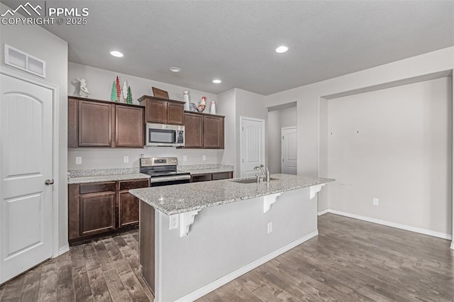 10726 Traders Pkwy, Fountain, CO 80817 - kitchen with stainless steel appliances, dark wood-style floors, a kitchen breakfast bar, an island with sink, and recessed lighting