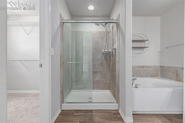 10726 Traders Pkwy, Fountain, CO 80817 - bathroom with a stall shower, a bath, a walk in closet, and wood finished floors