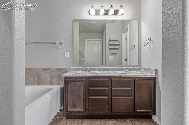 10726 Traders Pkwy, Fountain, CO 80817 - full bath featuring double vanity, a garden tub, and wood finished floors