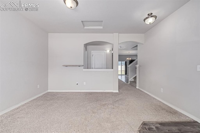 10726 Traders Pkwy, Fountain, CO 80817 - unfurnished living room featuring carpet, arched walkways, stairs, and a chandelier