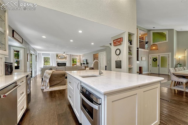970 Bend In The Trail Rd, Monument, CO 80132 - kitchen featuring open floor plan, appliances with stainless steel finishes, a fireplace, dark wood-style flooring, and white cabinetry