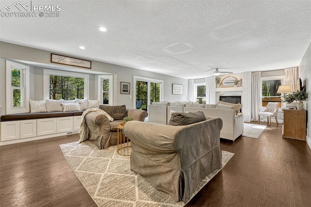 970 Bend In The Trail Rd, Monument, CO 80132 - living room with a textured ceiling, a ceiling fan, a brick fireplace, dark wood finished floors, and recessed lighting