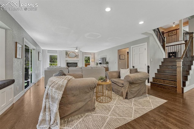 970 Bend In The Trail Rd, Monument, CO 80132 - living area featuring ceiling fan, wood finished floors, stairway, a fireplace, and a textured wall