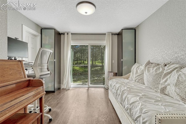 970 Bend In The Trail Rd, Monument, CO 80132 - bedroom featuring a textured wall, a textured ceiling, access to exterior, and wood finished floors
