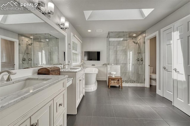 970 Bend In The Trail Rd, Monument, CO 80132 - full bathroom with a skylight, a shower stall, two vanities, a freestanding bath, and recessed lighting