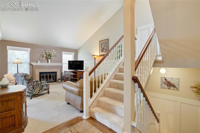 2527 Elite Ter, Colorado Springs, CO 80920 - living area featuring a decorative wall, a glass covered fireplace, vaulted ceiling, stairway, and a wainscoted wall