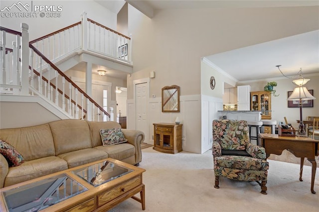 2527 Elite Ter, Colorado Springs, CO 80920 - living area featuring light colored carpet, stairs, crown molding, a wainscoted wall, and a high ceiling