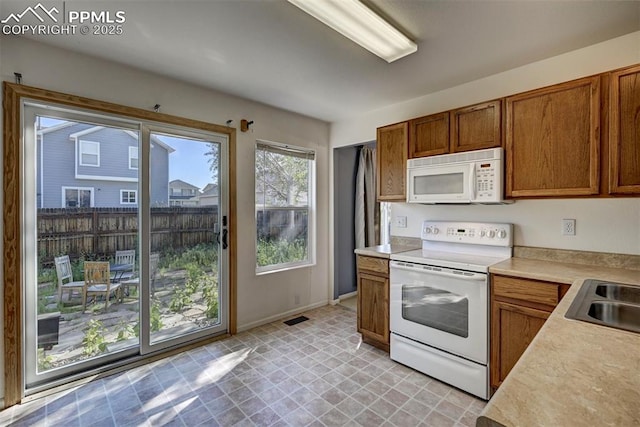 12874 Oakland Hills Rd, Peyton, CO 80831 - kitchen featuring white appliances, brown cabinets, and light countertops