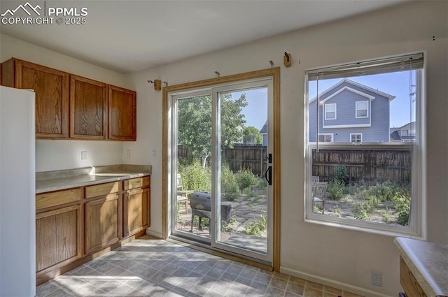 12874 Oakland Hills Rd, Peyton, CO 80831 - kitchen with freestanding refrigerator, brown cabinets, and light countertops