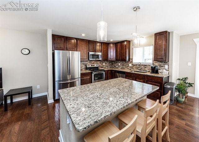 3730 Deep Haven Dr, Colorado Springs, CO 80920 - kitchen featuring appliances with stainless steel finishes, dark wood-style flooring, decorative backsplash, a center island, and a kitchen breakfast bar
