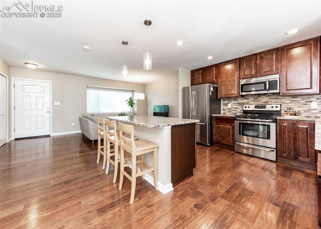 3730 Deep Haven Dr, Colorado Springs, CO 80920 - kitchen featuring stainless steel appliances, dark wood finished floors, backsplash, a breakfast bar, and hanging light fixtures