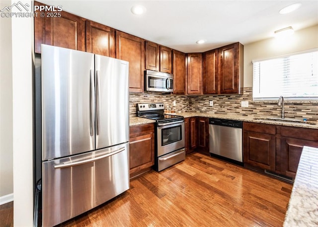 3730 Deep Haven Dr, Colorado Springs, CO 80920 - kitchen with stainless steel appliances, wood finished floors, tasteful backsplash, light stone countertops, and recessed lighting