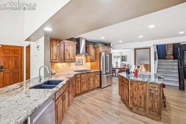 18971 Shadowood Dr, Monument, CO 80132 - kitchen featuring appliances with stainless steel finishes, wall chimney range hood, light wood finished floors, light stone countertops, and recessed lighting