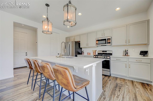 6237 Bodacious Cir, Colorado Springs, CO 80923 - kitchen featuring stainless steel appliances, light wood finished floors, an island with sink, light countertops, and a kitchen breakfast bar