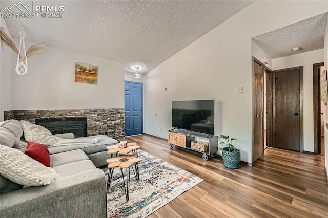3324 W Kiowa St, Colorado Springs, CO 80904 - living area featuring a textured ceiling, wood finished floors, a stone fireplace, and lofted ceiling
