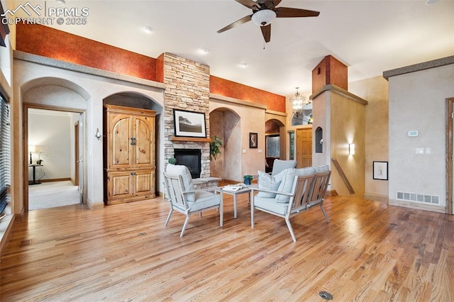 20401 High Pines Dr, Monument, CO 80132 - living room featuring a ceiling fan, light wood-style floors, arched walkways, and a stone fireplace