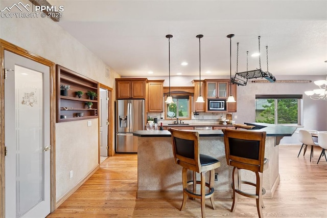 20401 High Pines Dr, Monument, CO 80132 - kitchen with appliances with stainless steel finishes, a center island, light wood-style floors, brown cabinetry, and a breakfast bar