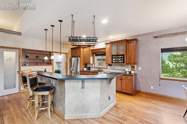 20401 High Pines Dr, Monument, CO 80132 - kitchen with stainless steel appliances, dark countertops, brown cabinetry, and light wood-style floors