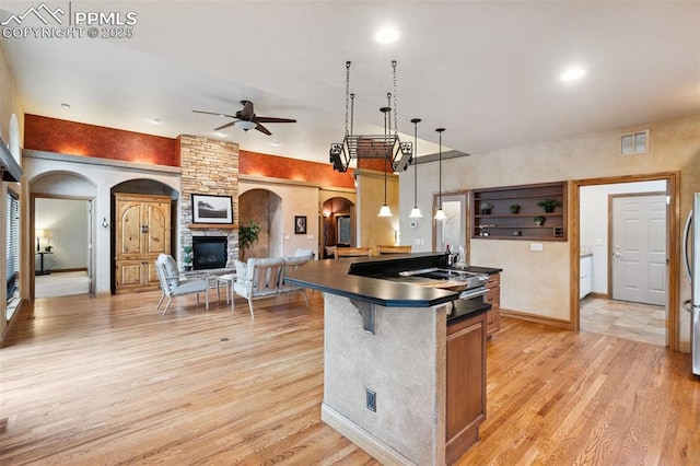 20401 High Pines Dr, Monument, CO 80132 - kitchen featuring arched walkways, a ceiling fan, light wood finished floors, dark countertops, and open floor plan