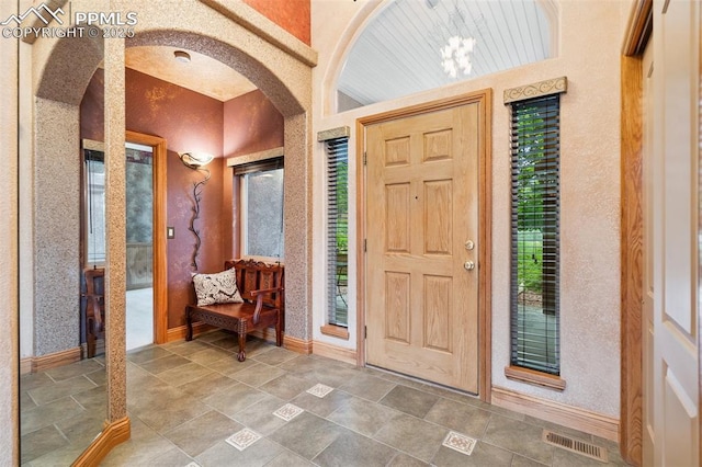 20401 High Pines Dr, Monument, CO 80132 - foyer entrance with arched walkways, a textured wall, and stone finish flooring