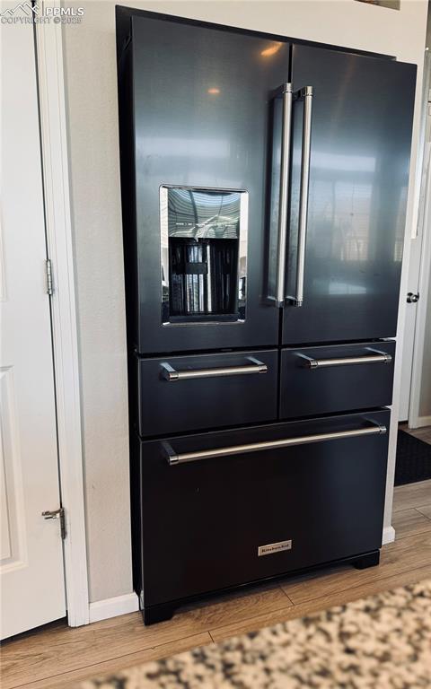 6640 Backcountry Loop, Colorado Springs, CO 80927 - detailed view of high end black refrigerator and wood finished floors