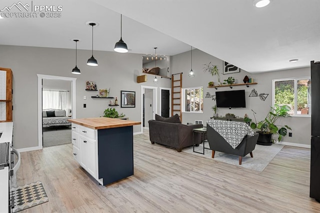 4540 Fountain Ave, Cascade, CO 80809 - kitchen featuring butcher block countertops, vaulted ceiling, light wood-style floors, white cabinets, and hanging light fixtures