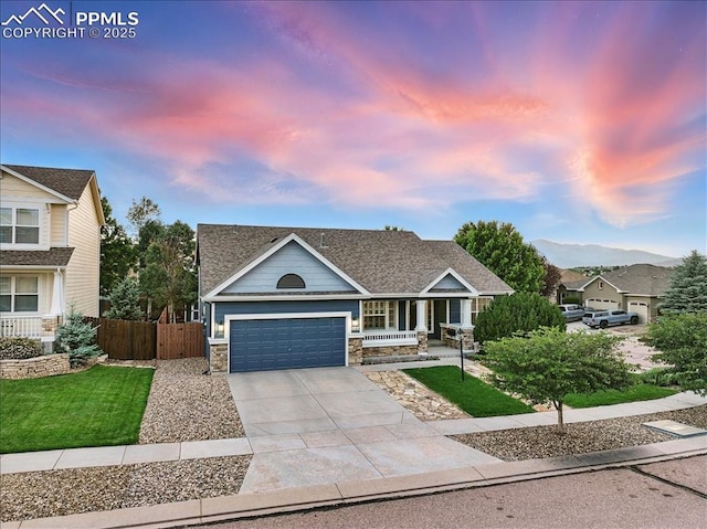 5584 Calamity Jane Ln, Colorado Springs, CO 80923 - craftsman house featuring covered porch, stone siding, a garage, concrete driveway, and roof with shingles
