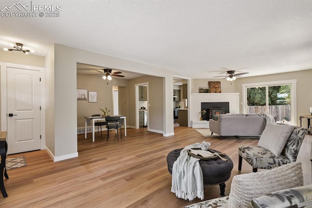 79 W Old Broadmoor Rd, Colorado Springs, CO 80906 - living area featuring a ceiling fan, light wood-style flooring, a textured ceiling, and a brick fireplace