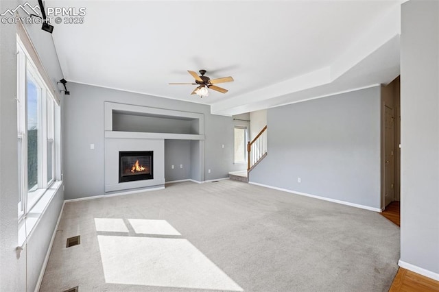 1562 Lookout Springs Dr, Colorado Springs, CO 80921 - unfurnished living room with stairs, a glass covered fireplace, a ceiling fan, carpet, and built in features