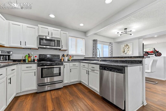 245 Turf Trail Pl, Fountain, CO 80817 - kitchen with appliances with stainless steel finishes, a peninsula, white cabinetry, dark wood-style flooring, and recessed lighting